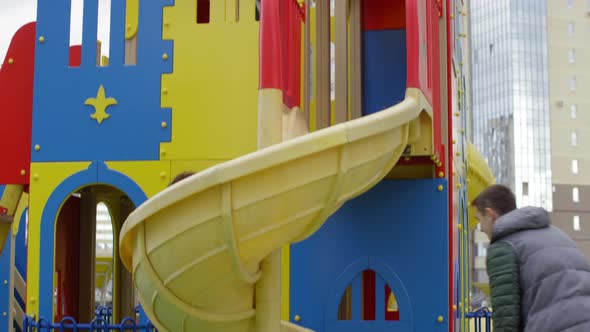 Caucasian Mom and Son Going down Slide Together and Dad Catching alt