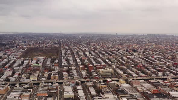 a high aerial drone shot, panning right over Sunset Park Brooklyn. It's a cloudy day & the Belt Park