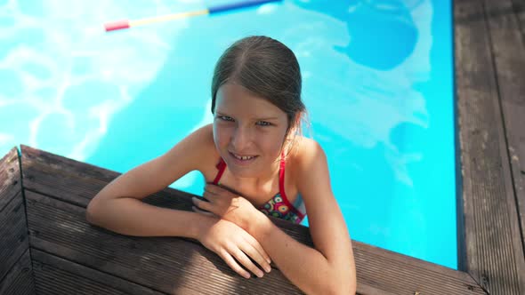 High Angle View of Cute Caucasian Girl Posing at Poolside in Azure Blue Water in Slow Motion