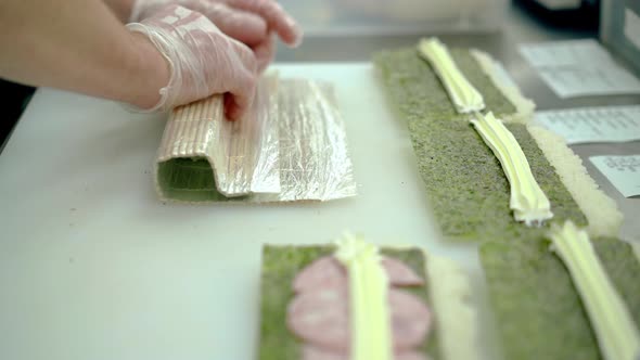 Cook Prepares Japanese Rolls Wraps Ingredients in Rice and Nori Seaweed Using a Mat