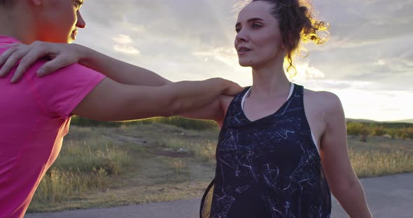 Two Multiethnic Girls Stretching Together in the Street Stretching Their Legs Before a Run