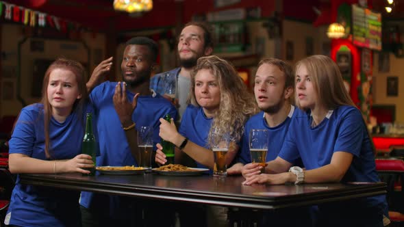 A Group of Friends of Fans in Blue Tshirts Excitedly Emotionally Watch the Match and Rejoice at the