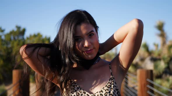 A beautiful young hispanic woman fashion model tying a bandana and staring with a smile in an outdoo