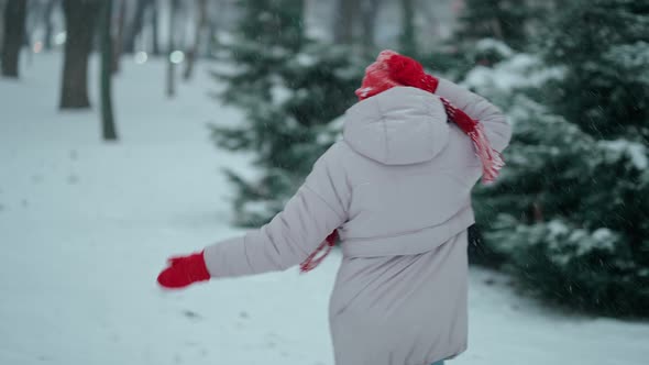 Camera Follows Happy Excited Woman Walking and Playfully Running in Park at Snowfall Time