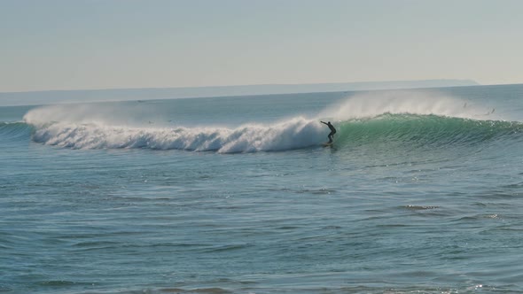 Surfer catching a big wave of the Atlantic Ocean on a beautiful sunny day