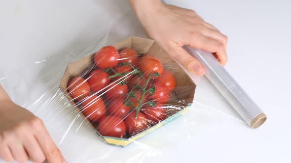 Woman Using Food Film for Food Storage on a White Table