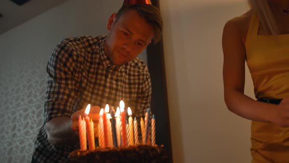 Sexy Lady and Handsome Guy Lights Candles on Tasty Birthday Cake. Prepearing for Party.