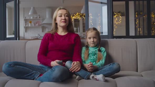 Mother and Daughter Watching Tv on Sofa at Home