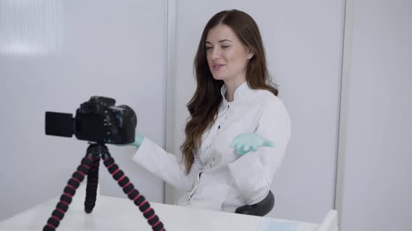 Happy Female Doctor in Uniform Recording Lesson in Front of Vlogging Camera