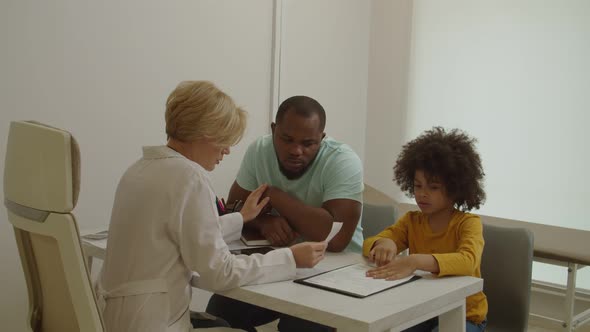 Empathetic Woman Doctor Telling Bad News to Upset Black Father About Illness of Little Son at Clinic