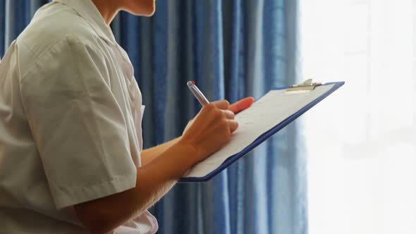 Smiling doctor writing on clipboard 4k