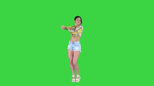 Girl in Square Shirt and Jeans Shorts, Sneakers, Dancing on a Green Screen, Chroma Key.