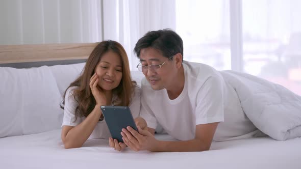 Happy senior couple using tablet computer together on the bed