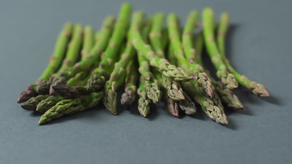 Video of close up of fresh asparagus over grey background