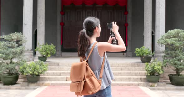 Woman holding camera to take video and walk into chinese temple