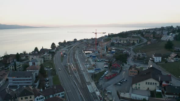 Aerial of large crane at construction site in small town near beautiful lake