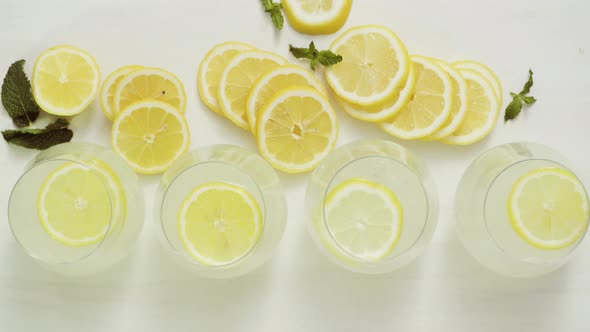 Fresh lemonade in a drinking glasses garnished with sliced of lemon and mint.