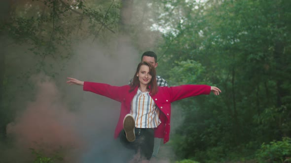 Young Couple in Clouds of Color Smoke Outdoor