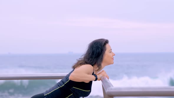 Active Woman in Sport Clothes on the Seashore Doing Sport Exercises