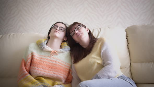 Sad Mom and Daughter Are Sitting on the Sofa and Watching Tv at Home