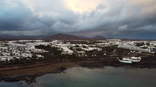 Aerial view storm clouds over a volcano and coastal town in Lanzarote