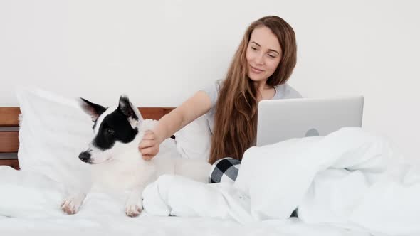 Girl with Laptop and Dog in the Bed