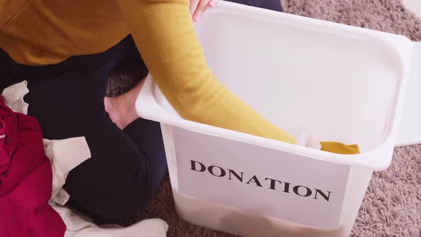 Closu up of woman selecting clothes for donation and putting them in a box. Concept campaign to dona