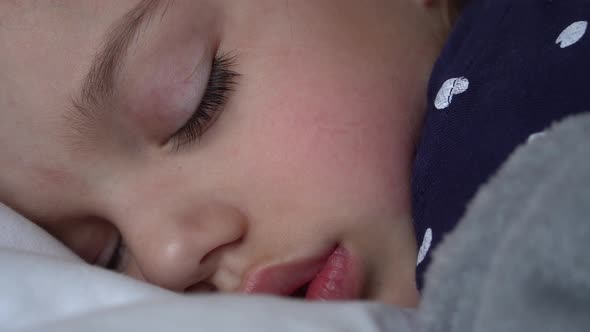 Authentic Cute Little Girl Sleeping Sweetly In Comfortable White and Grey Bed Close Up