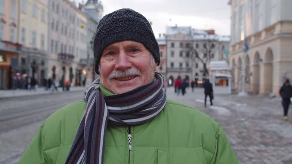 Portrait of Old Senior Man Tourist Smiling Looking at Camera in Winter City Center of Lviv Ukraine