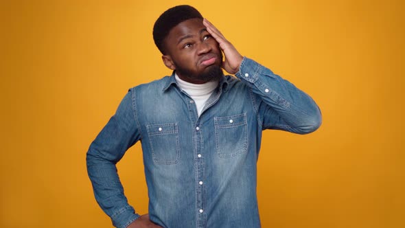 Young African American Man Thinking Against Yellow Background