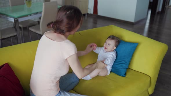 Young Woman Holding Her Joyful Newborn Child and Playing with Him