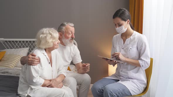 Doctor on Home Visit in Elderly Listens to Symptoms and Complaints Writes Down on Digital Tablet