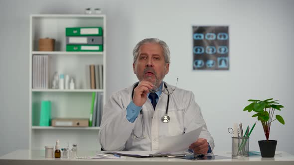 Aged Male Doctor Reviews the Patient's Medical History and Concentrates on the Treatment Options