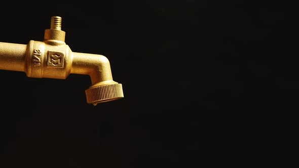 Faucet is dripping and flowing slowly on a black background