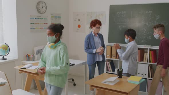 Teacher Sanitizing Hands of Children Before Lesson