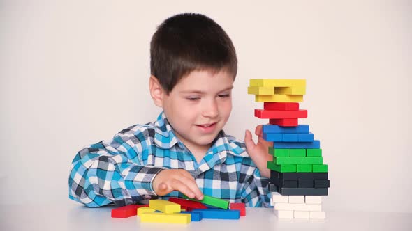 A 4Yearold Boy Plays a Board Game of Jenga Pulling Multicolored Blocks Out of the Tower