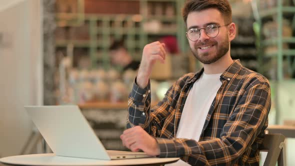 Thumbs Up By Young Man Working in Cafe