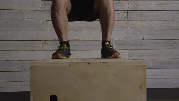 Lower half of man working out as he jumps on wood box