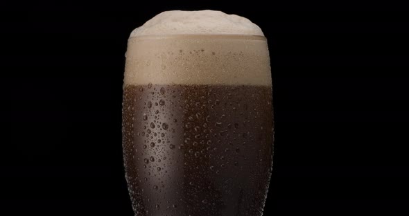 Glass of black beer on a black background.