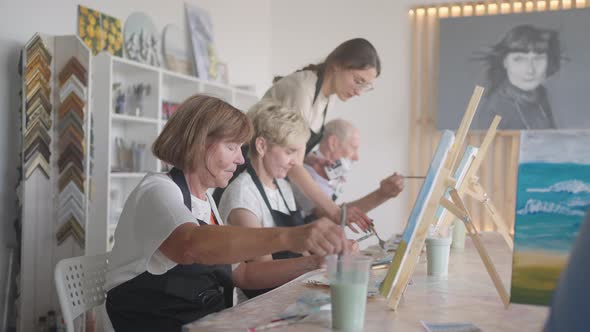 High Angle View of Cheerful Senior Friends Painting on Canvas