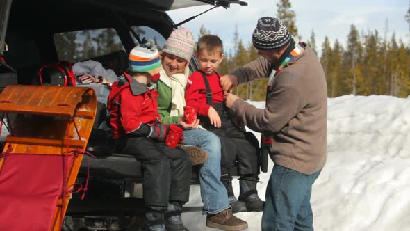 Family having hot chocolate and preparing to go sledding