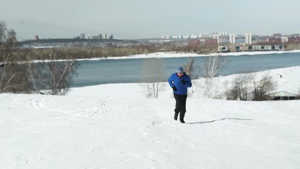 Man Running Up The Hill In Winter