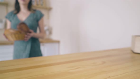 Woman Puts Wicker Basket with Homemade Bread on Table