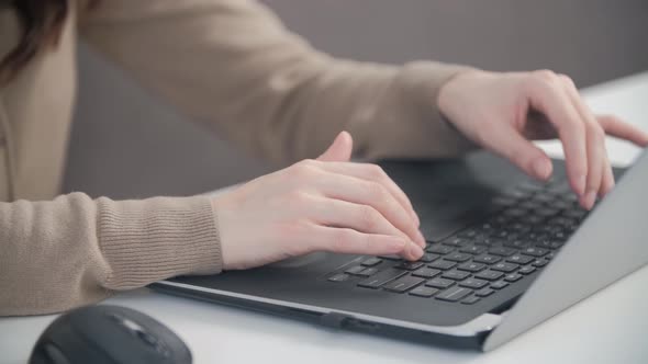 Woman works from home during lockdown, typing text on laptop computer keyboard