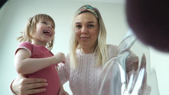 Mother with Daughter Open Hatch of Washing Machine and Take Out Toy