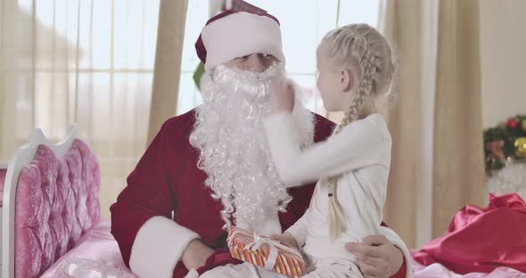 Cheerful Caucasian Blond Girl Taking Off Father's False Beard. Daughter Revealing Secret of Positive