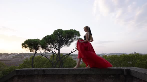 Woman dancing on a balcony in Spain the girl is wearing a red skirt, sunset in the morning with beau