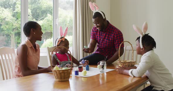 African american family painting easter eggs together at home