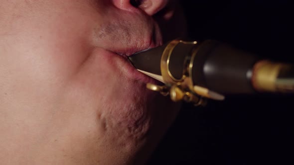 Male Saxophonist Blows Mouth Into Mouthpiece of a Saxophone in Closeup
