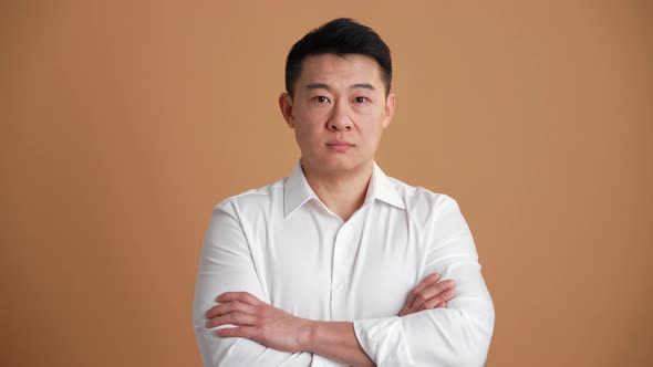 Concentrated Asian businessman looking at the camera with crossed hands